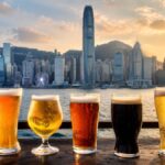 香港のランドマークを背景に冷えたビールグラスが並ぶシーン