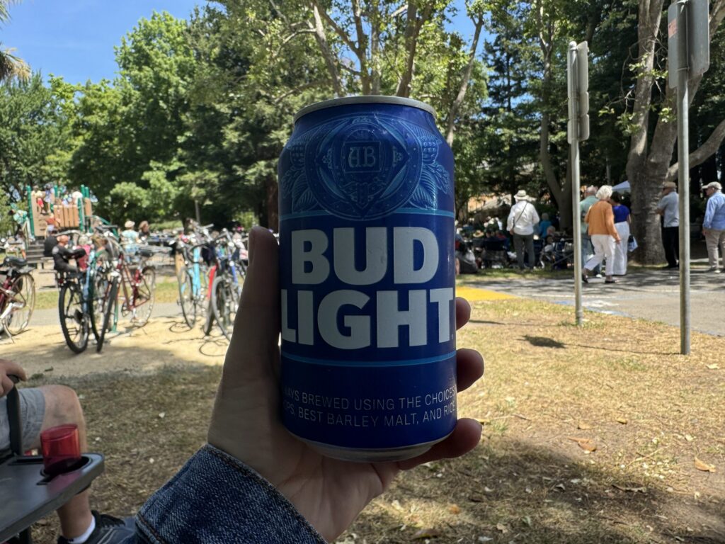 屋外で手に持った青い缶のBud Light